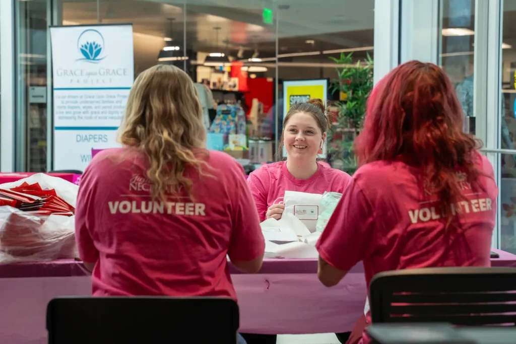 A group of young women wearing Justice Necessary volunteer shirts at a volunteer event.