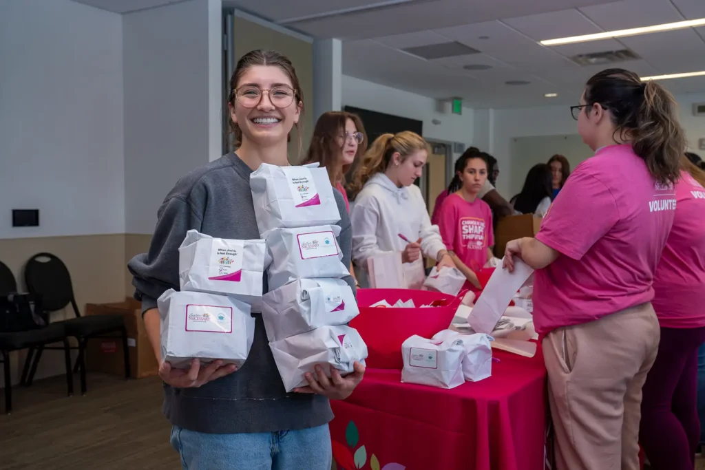 A young woman carries multiple bags full of donated period products.